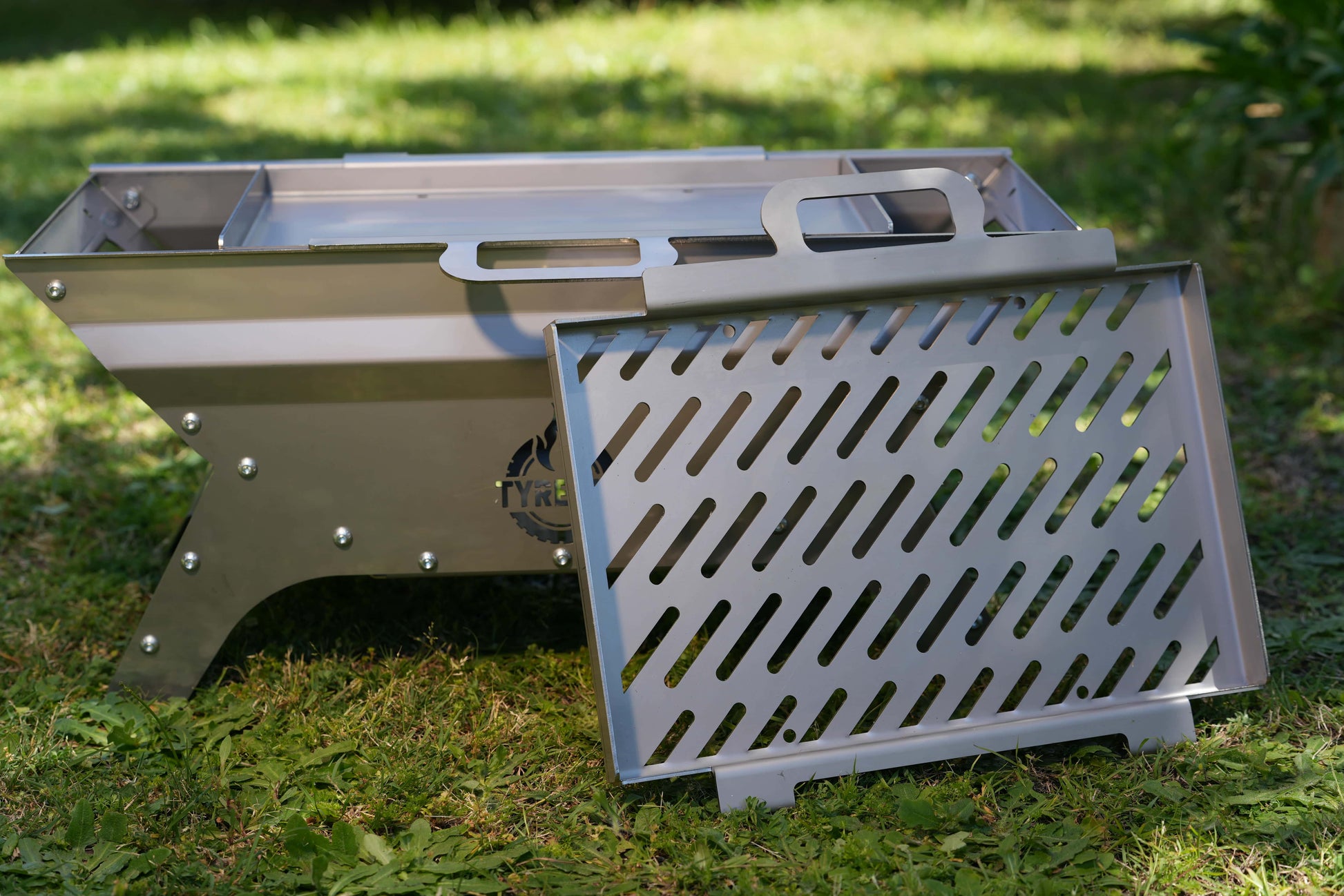 Tyre Fire bbq / fire pit with the stainless steel grilling plate sitting in front of it.